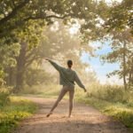 Rear view of a person in light activewear stretching gracefully on a sunlit forest path, surrounded by lush green trees.